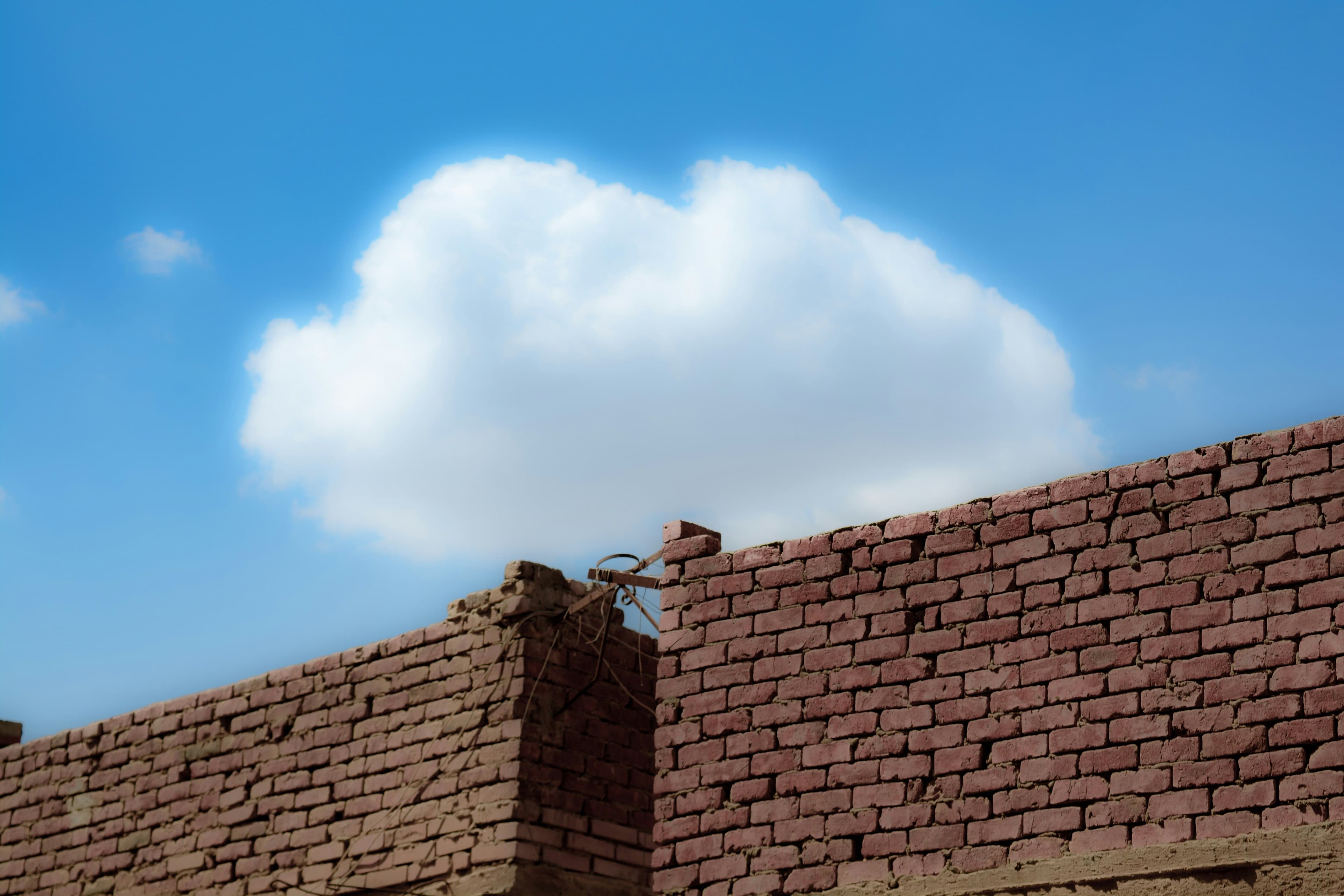 a brick wall with a cloud in the sky behind it .