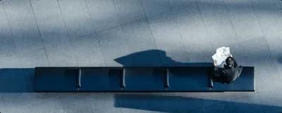 Man on a blue bench reading a news paper