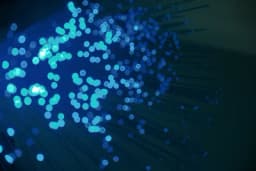 a bunch of blue dots are floating in the air on a dark background .