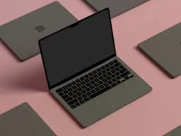 a group of laptops are sitting on top of each other on a pink surface .