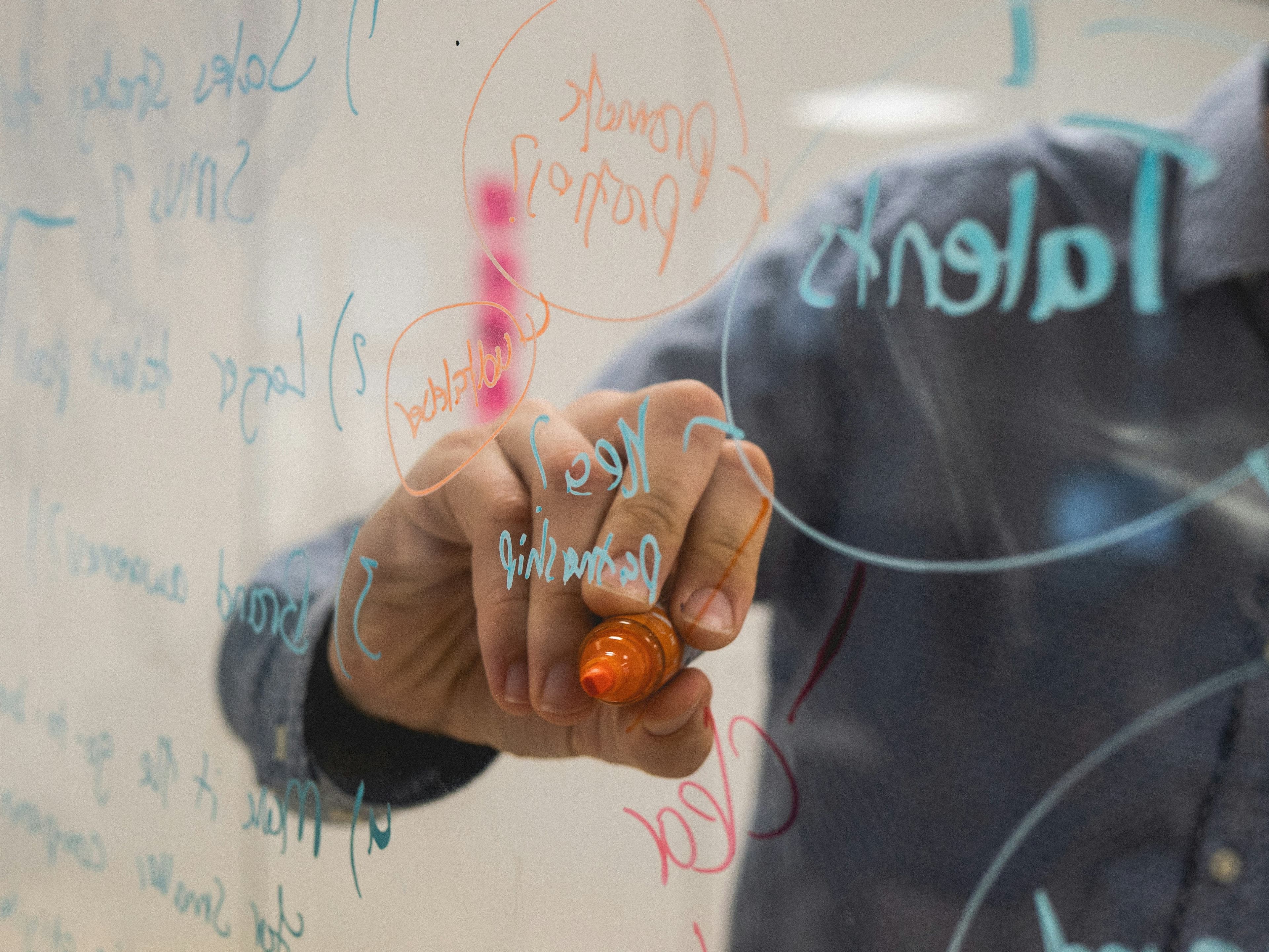 a person is writing on a whiteboard with a marker .
